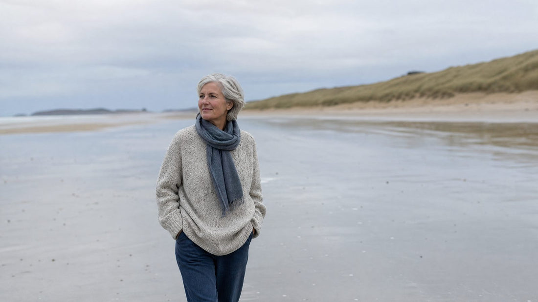 Femme de 66 ans marchant sur une plage bretonne par temps frais, joues rosies par le vent